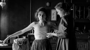 A still from "The Girl with the Needle" (2024), showcasing its haunting black-and-white cinematography, capturing the eerie atmosphere of 1919 Copenhagen.