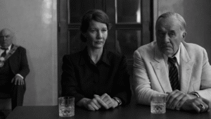 Black-and-white still from Fatherland showing Sandra Hüller as Erika Mann and Hanns Zischler as Thomas Mann seated at a table in Paweł Pawlikowski’s Cannes Film Festival drama.